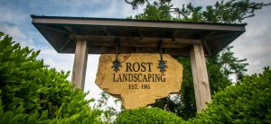 Rost Landscaping sign among green shrubbery