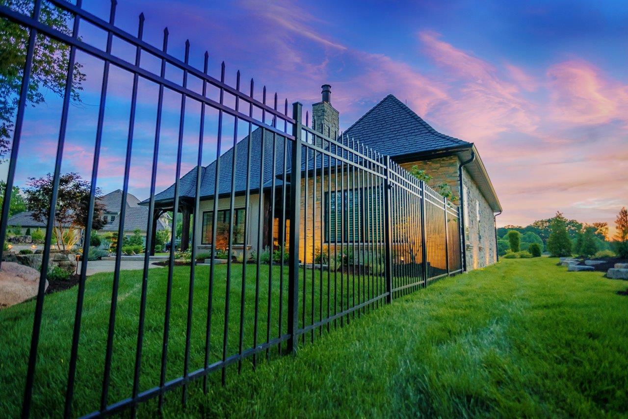 Ornamental fencing in backyard with freshly cut green grass.