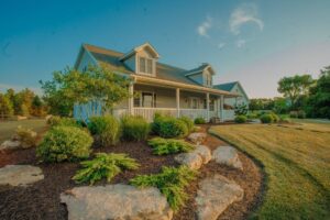 stone a shrub landscaping leading up to house with covered porch