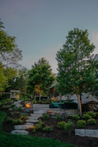 Stone retaining walls and stair with landscaping on either side leading to home during sunset