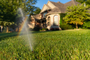 up close or a rain from a sprinkler watering grass in front of a house