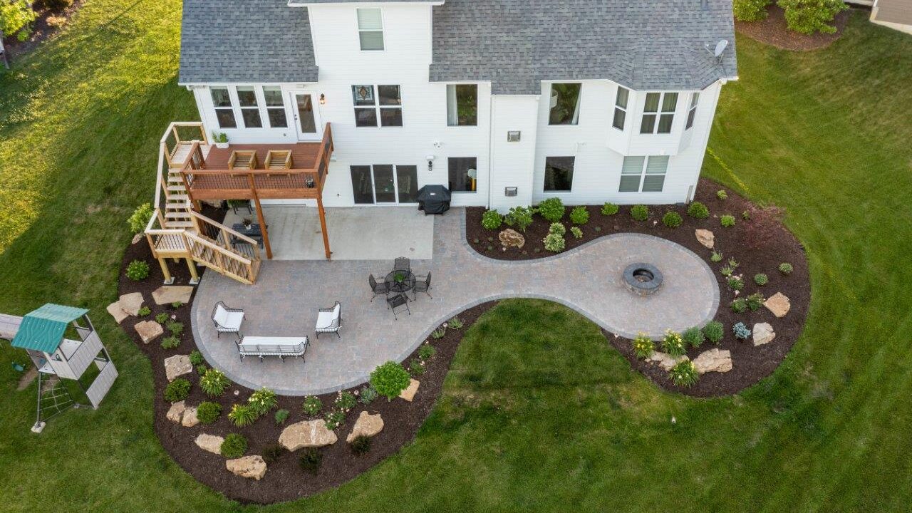 aerial view of patio and deck with surrounding landscaping attached to house