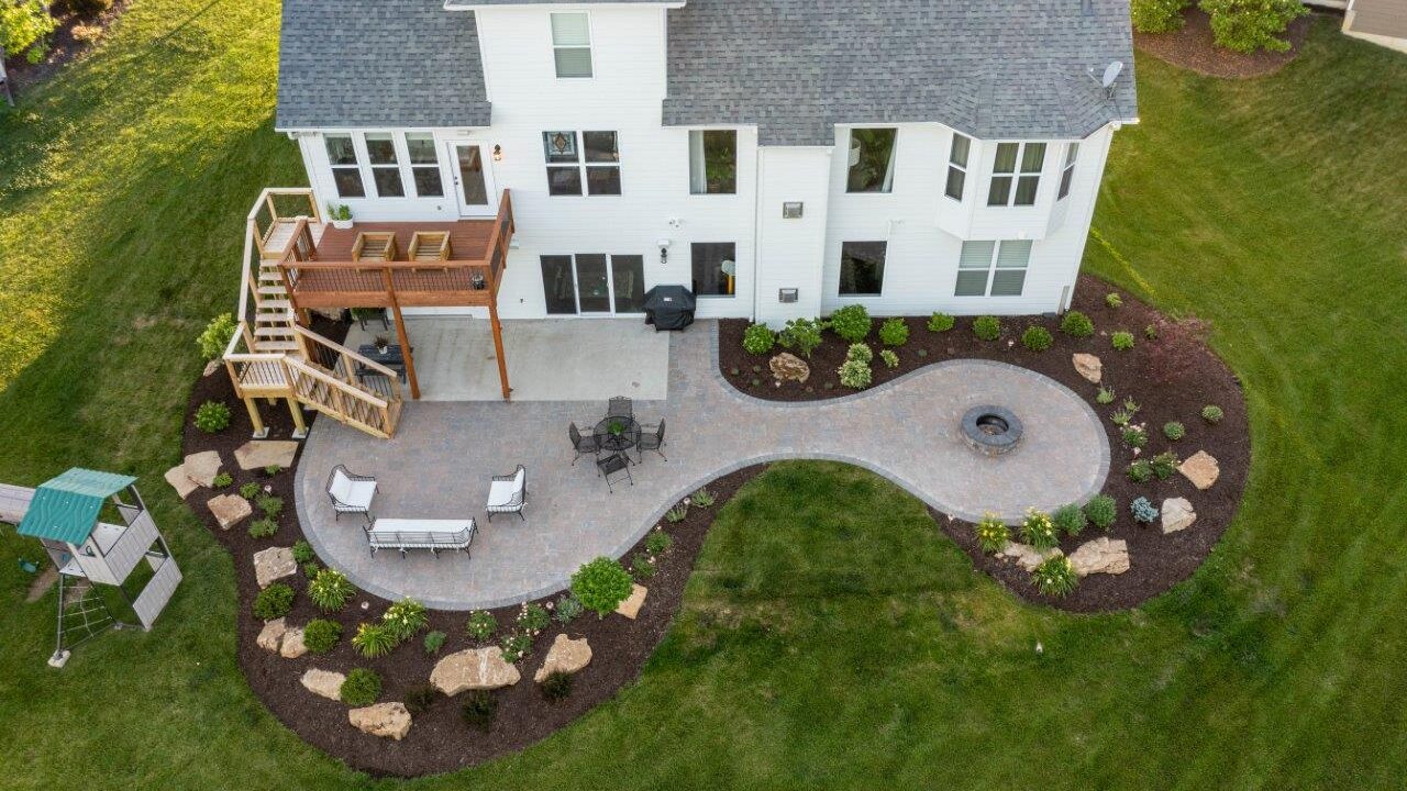aerial view of patio and deck with surrounding landscaping attached to house