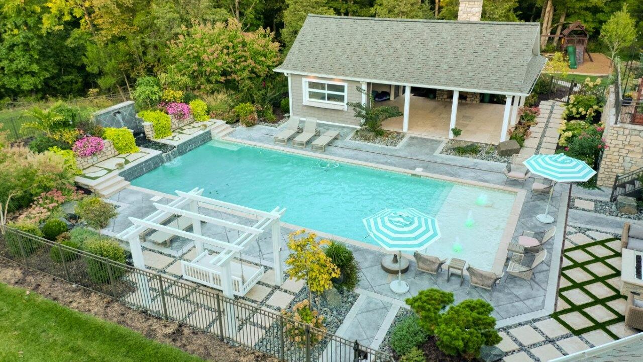 aerial view of pool with water feature and seating next to pool house