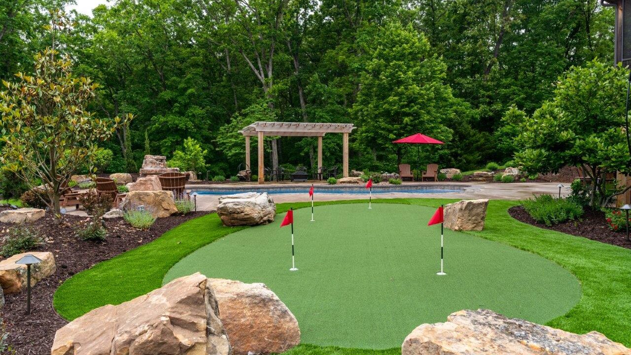 putting green in yard suranded by landscaping bed and stones