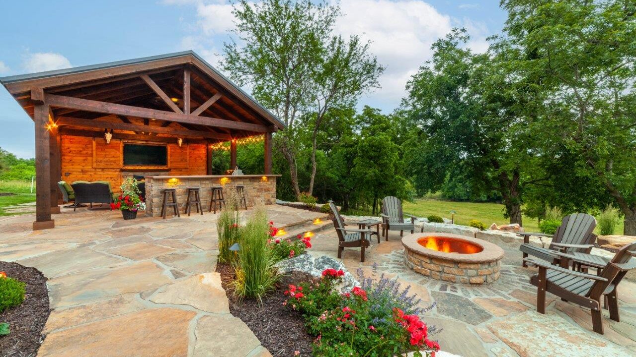 outdoor covered kitchen wit nearby seating area on a stone patio