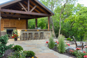 covered outdoor kitchen with stone bar and fireplace