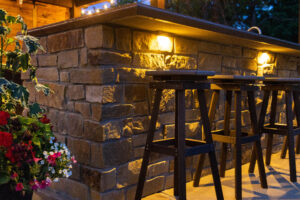 lit outdoor stone bar with stools outdoor at night