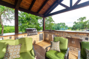 covered outdoor kitchen with sink, grill and cushoned seating area