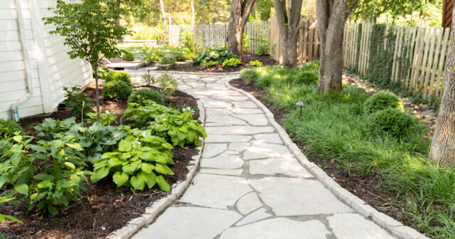 mortared flagstone walkway through a landscaped yard