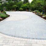 driveway with pavers layed out in a curved design surrounded by trees and greenery