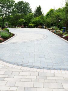 driveway with pavers layed out in a curved design surrounded by trees and greenery