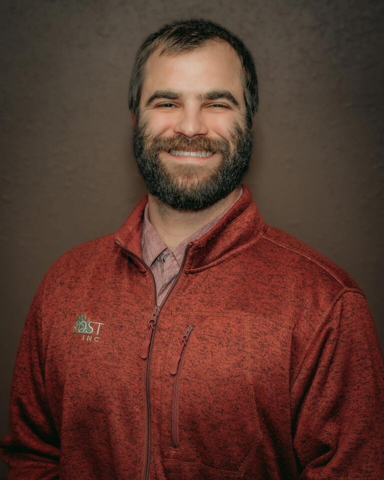 Headshot of Irrigation, Lighting, Fencing Manager Austin McBride with a smile and red Rost polo